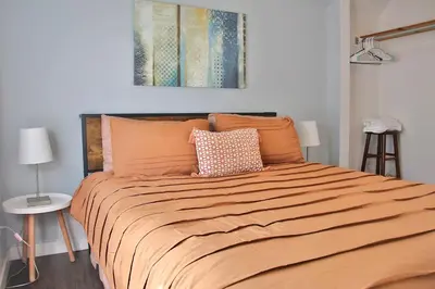 a bedroom with a large bed with an orange blanket at The Ultimate Lakewood Retreat! in Lakewood