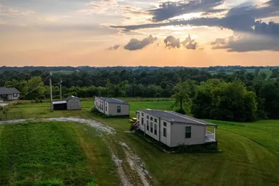two houses in a field with the sunset in the background at Rustic Mt Sterling Cabin2 Near Downtown Pets OK in Mount Sterling