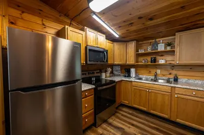 a kitchen with a stainless steel refrigerator and wooden cabinets at Rustic Mt Sterling Cabin2 Near Downtown Pets OK in Mount Sterling