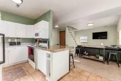 a large kitchen with white cabinets and a tv at The Mad Cat Inn in Lewis Center
