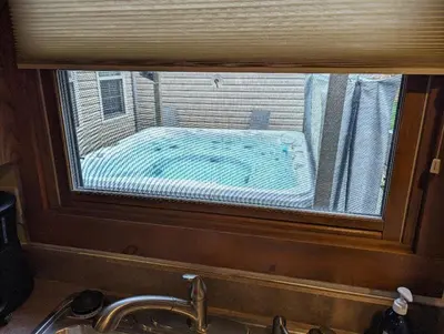 a window over a sink with a view of a house at The Lazy Cat Lodge in Lewis Center
