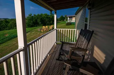 a rocking chair on the porch of a house at Rustic Mt Sterling Cabin1 Near Downtown Pets OK in Mount Sterling
