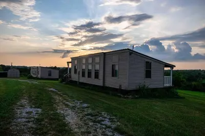 a small house on a field with a cloudy sky at Rustic Mt Sterling Cabin1 Near Downtown Pets OK in Mount Sterling