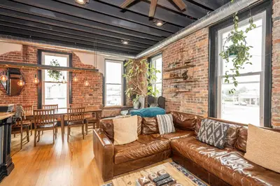 a living room with a leather couch and a brick wall at The Brick Dachshund - Chic for 9