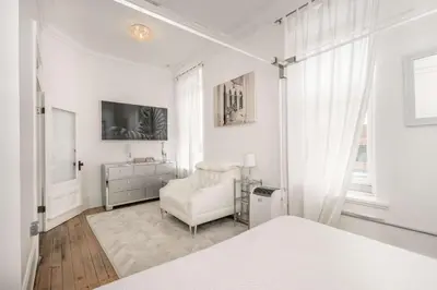 a white bedroom with a bed and a chair at The Brick Dachshund - Chic for 9
