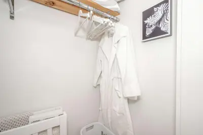 a closet with a white robe hanging on a wall at The Brick Dachshund - Chic for 9