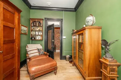 a room with green walls and a chair and a clock at The Brick Dachshund - Chic for 9