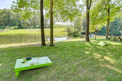 a green bench sitting on the grass near a lake at Ohio Amish Country Getaway Fish, Hike, Boat! in Sugarcreek