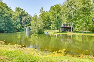 a view of a lake with a house in the distance at Ohio Amish Country Getaway Fish, Hike, Boat! in Sugarcreek