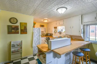 a kitchen with white cabinets and a counter with stools at Boat and Unwind! Charming Atwood Lake Farmhouse in Dellroy