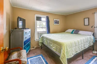 a bedroom with a bed and a tv and a window at Boat and Unwind! Charming Atwood Lake Farmhouse in Dellroy