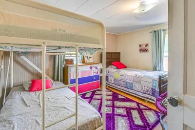 two bunk beds in a room with purple carpet at Boat and Unwind! Charming Atwood Lake Farmhouse in Dellroy