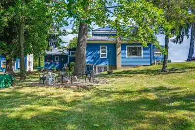 a blue house with a table and chairs in a yard at Boat and Unwind! Charming Atwood Lake Farmhouse in Dellroy