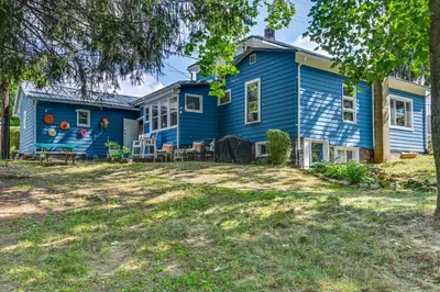 a blue house with a yard at Boat and Unwind! Charming Atwood Lake Farmhouse in Dellroy