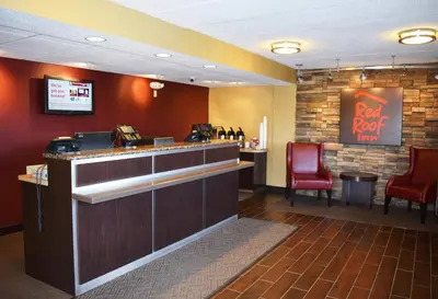 a restaurant with a bar with two red chairs at Red Roof Inn St Clairsville - Wheeling West in Saint Clairsville