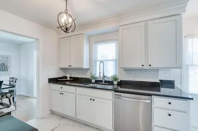 a white kitchen with white cabinets and a sink at Stylish 3BR w Sunroom & Deck in Cleveland