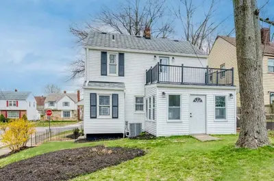 a white house with a tree in the yard at Stylish 3BR w Sunroom & Deck in Cleveland