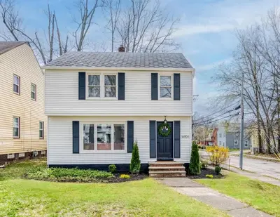 a white house with a black door at Stylish 3BR w Sunroom & Deck in Cleveland