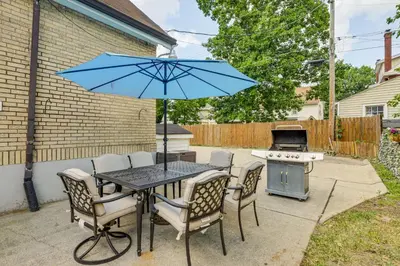 a table and chairs with a blue umbrella and a grill at Modern Group Getaway with Private Yard in Cincinnati in Cincinnati