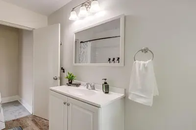 a white bathroom with a sink and a mirror at 6 Mi to Ohio State Walkable Home in S Columbus! in Columbus