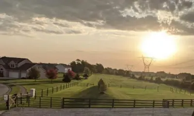 a field with a fence and the sun in the sky at The Calico Cottage in Lewis Center