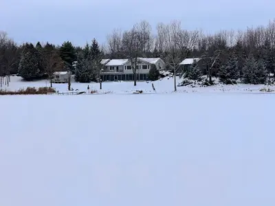 a large house with snow on the ground at Whispering Pines Auburn in Auburn