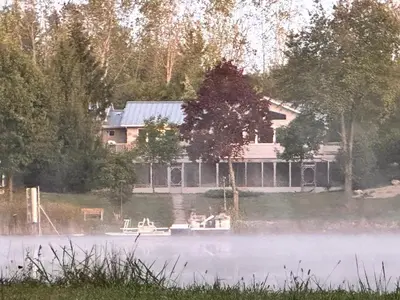 a house on a lake with fog in the foreground at Whispering Pines Auburn in Auburn