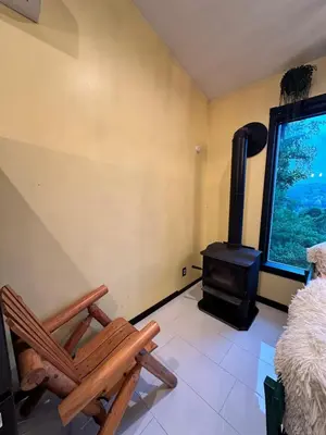 a room with a wood stove and a chair at Buddhas Little Cabin! 1 min from Palace of Gold in Moundsville
