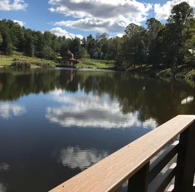 a view of a lake with a wooden pier at Buddhas Little Cabin! 1 min from Palace of Gold in Moundsville
