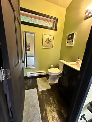 a bathroom with a toilet and a sink and a mirror at Buddhas Little Cabin! 1 min from Palace of Gold in Moundsville