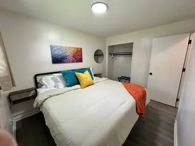 a bedroom with a large white bed with colorful pillows at KING bed, Pet Friendly, Modern Retreat in CLE-BW in Berea