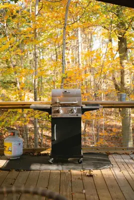 a grill sitting on a deck in the woods at The Treetop Retreat – Family Getaway in Scenic Hocking Hills in Logan