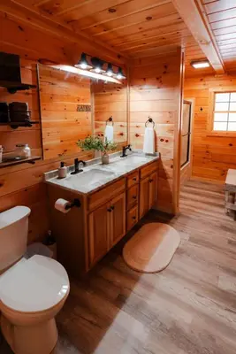 a bathroom with a toilet and a sink in a log cabin at Sleeps 16! Luxury Cabin with Game Room & Hot Tub in Nelsonville