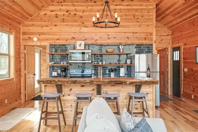 a kitchen with a large island in a log cabin at Fern Haven A modern take on Hocking Hills cabins in McArthur