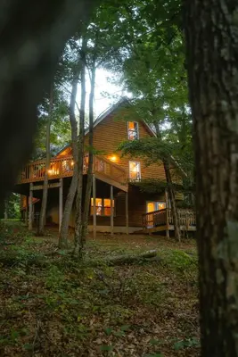 a large wooden house in the woods with trees at Cheerful Two Bdrm Cabin with Hot Tub & Pet Friendly in Lancaster