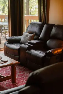 a black leather couch in a living room at Cheerful Two Bdrm Cabin with Hot Tub & Pet Friendly in Lancaster