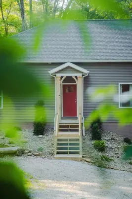a house with a red door and a porch at Modern 2 BD cabin with hot tub & Games & Central Loc in Rockbridge