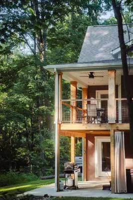 a house with a wrap around deck in the woods at Modern 2 BD cabin with hot tub & Games & Central Loc in Rockbridge