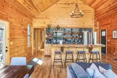 a log cabin kitchen with a bar and stools at Modern Luxury I Hot Tub I Hiking in McArthur