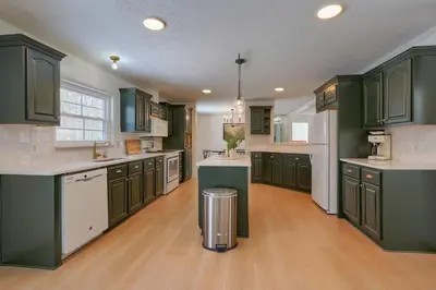 a large kitchen with green cabinets and white appliances at Buckingham Woods I Hocking Hills in Logan