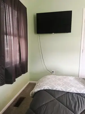 a bedroom with a bed and a flat screen tv on the wall at Blue Heron Cottage with Game Room, Deck & Hot Tub in Logan
