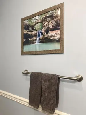 a picture of a waterfall hanging on a wall with towels at Blue Heron Cottage with Game Room, Deck & Hot Tub in Logan
