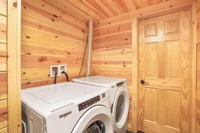 a laundry room with a washer and dryer in a log cabin at Fern Woods A modern take on Hocking Hills cabins in McArthur