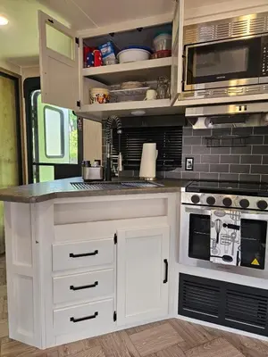 an rv kitchen with white cabinets and appliances at Tranquil Stay Close to Hotspots