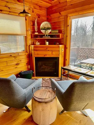a living room with two chairs and a fireplace at Fern Hill Cabin in McArthur