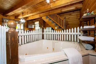 a white tub in a room with a wooden fence at Honey Bear Cabin in Millersburg