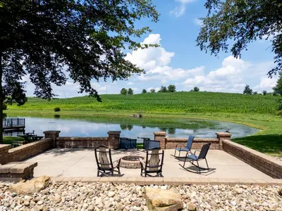 a patio with chairs and a fire pit in front of a pond at Honey Bear Cabin in Millersburg