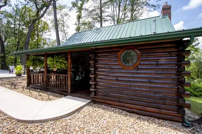 a log cabin with a porch and a green roof at Honey Bear Cabin in Millersburg