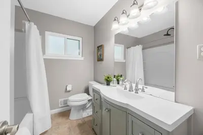 a bathroom with a sink and a toilet and a mirror at Spacious 5BR Firepit with Deck Near OSU and More in Columbus