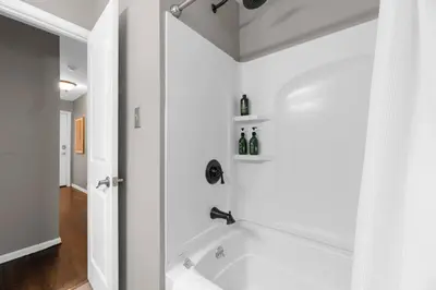 a white bathroom with a tub and a shower at Spacious 5BR Firepit with Deck Near OSU and More in Columbus